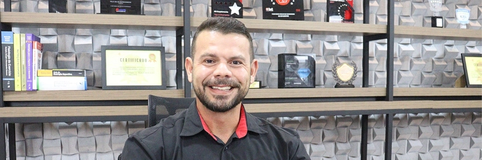 Growth Supplements - nutricionista esportivo sorrindo em escritório com prateleiras e certificados