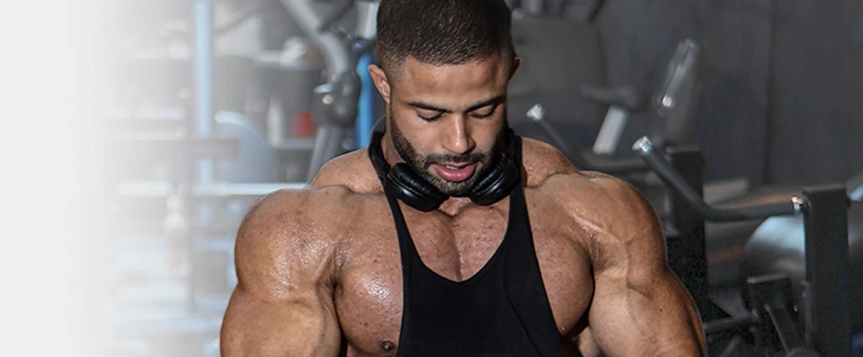 Growth Supplements - fisiculturista com fones no pescoço durante treino na academia