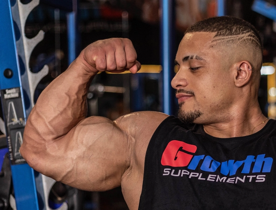 Atleta musculoso sexo masculino flexionando o bíceps na academia