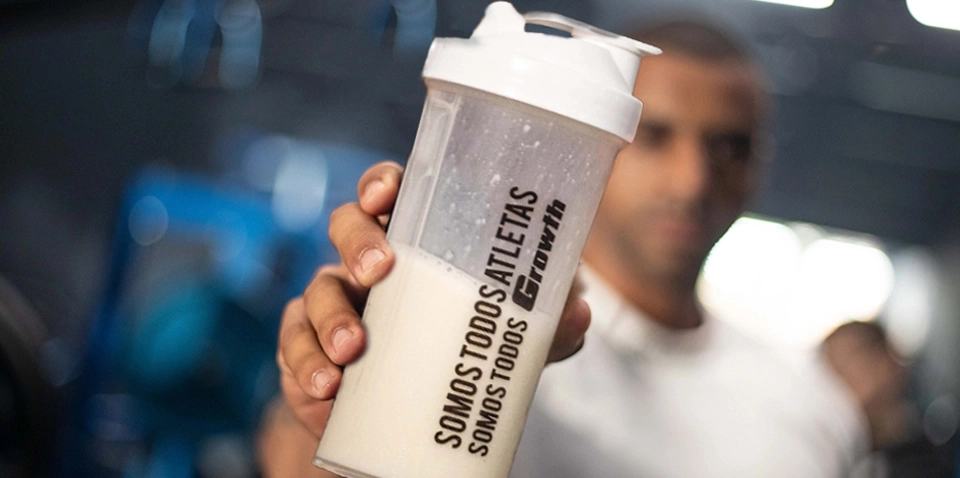 Mão segurando dosador de proteína em pó branco