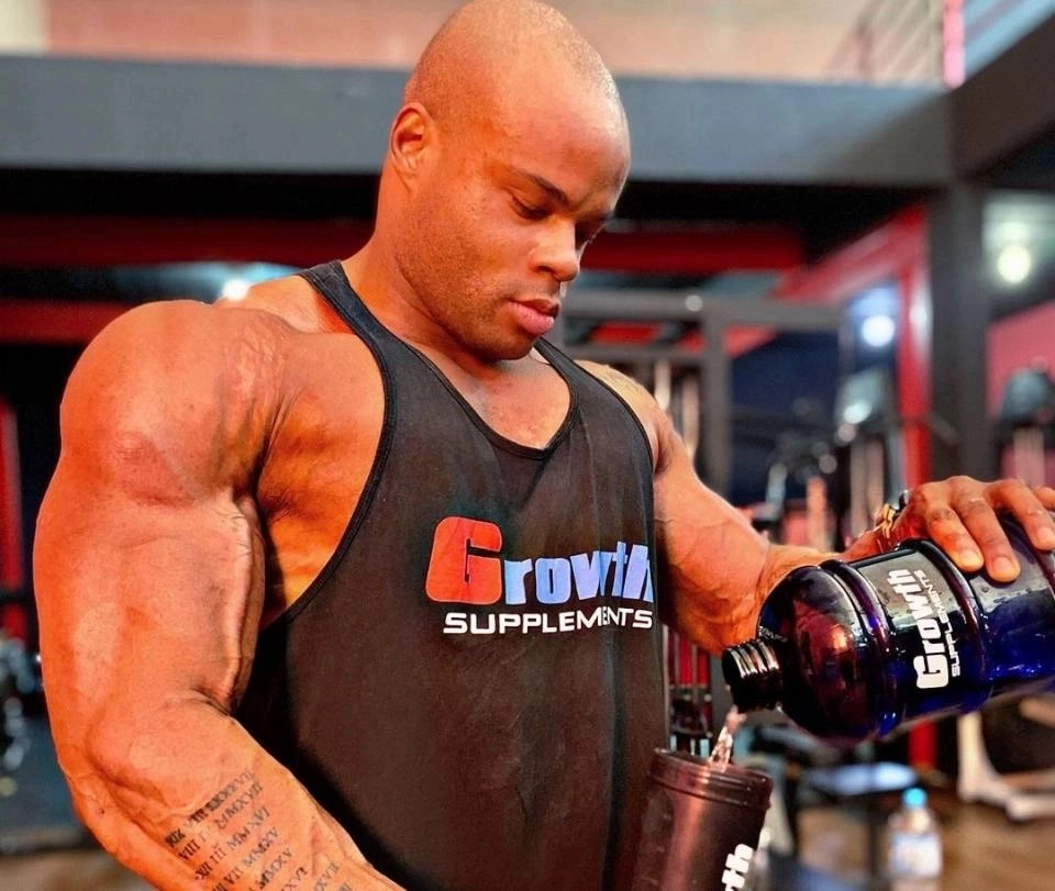 Atleta musculoso concentrado e suado durante sessão de treino na academia