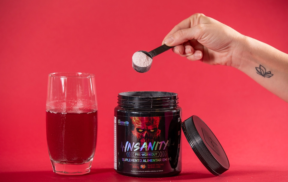 Pré-treino Insanity 300g - Growth Supplements, com um copo ao lado