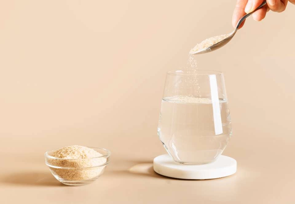 GROWTH SUPPLEMENTS - Imagem ilustrativa colher colocando 100% psyllium em copo de água