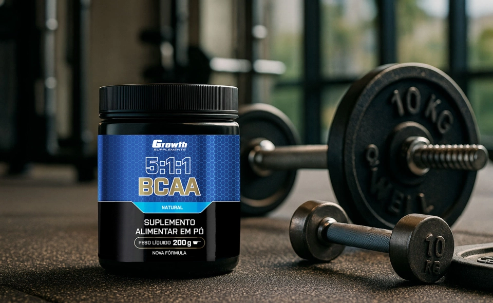 BCAA (5:1:1) (200g) (em pó) - Growth Supplements ao lado de halteres de uma academia